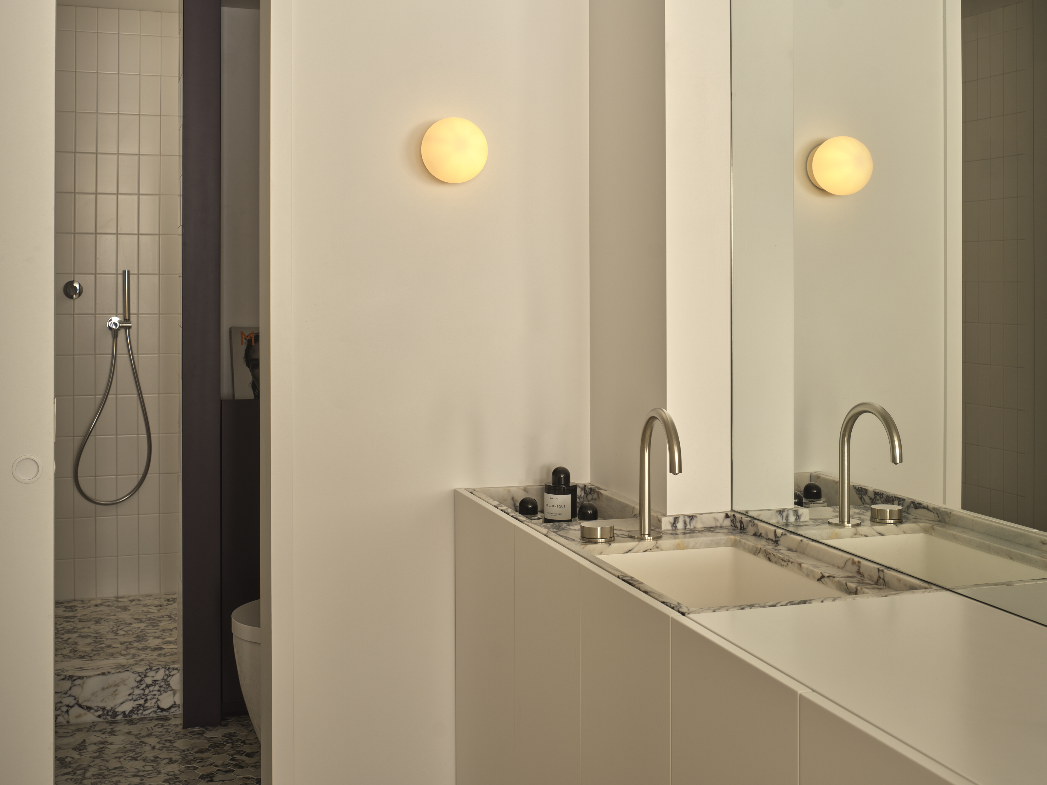 Bathroom with double marble vanity, globe sconces, and walk-in shower