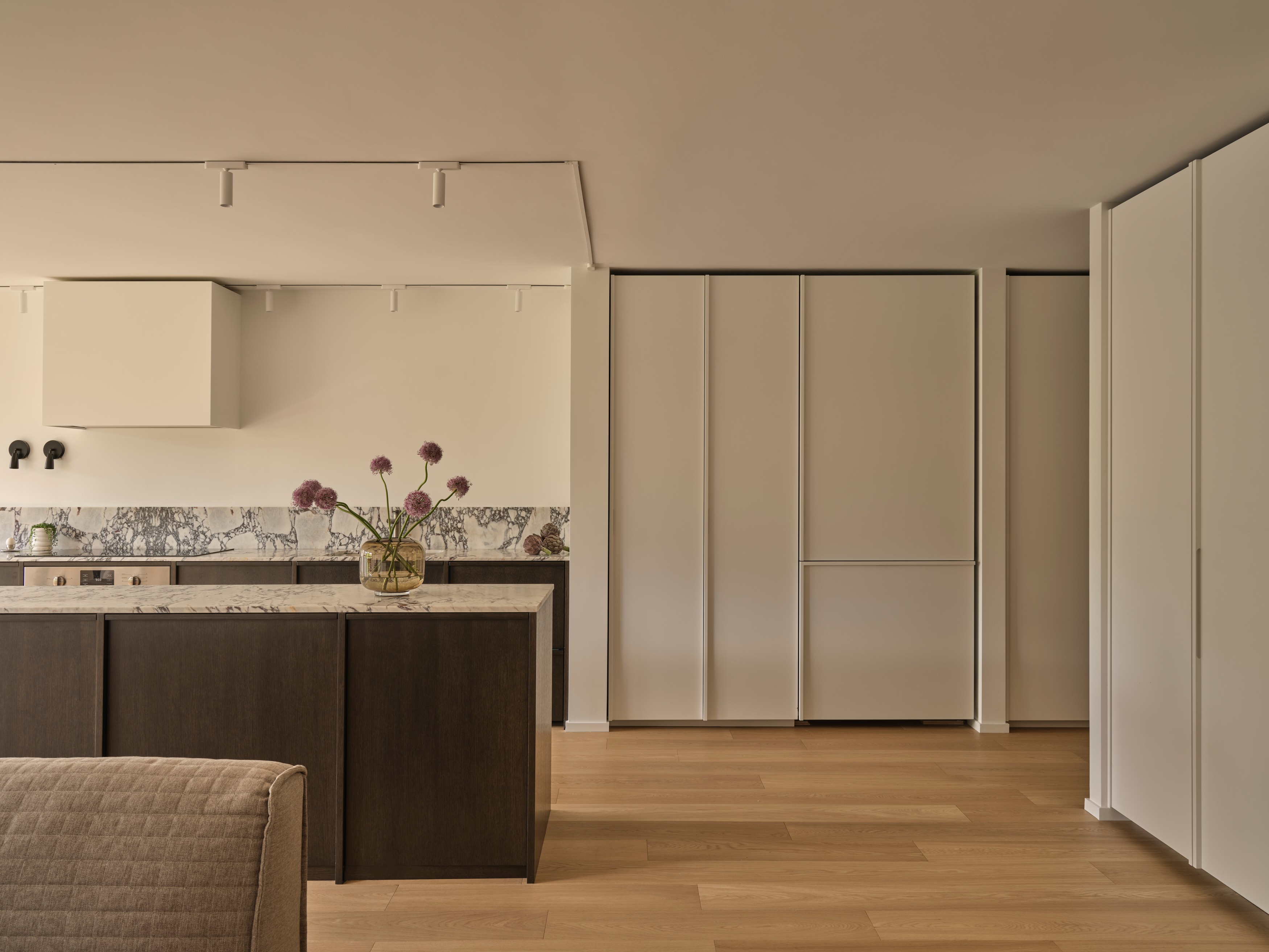 Open-plan kitchen with Calacatta Viola marble waterfall island, range hood, and woven counter stools