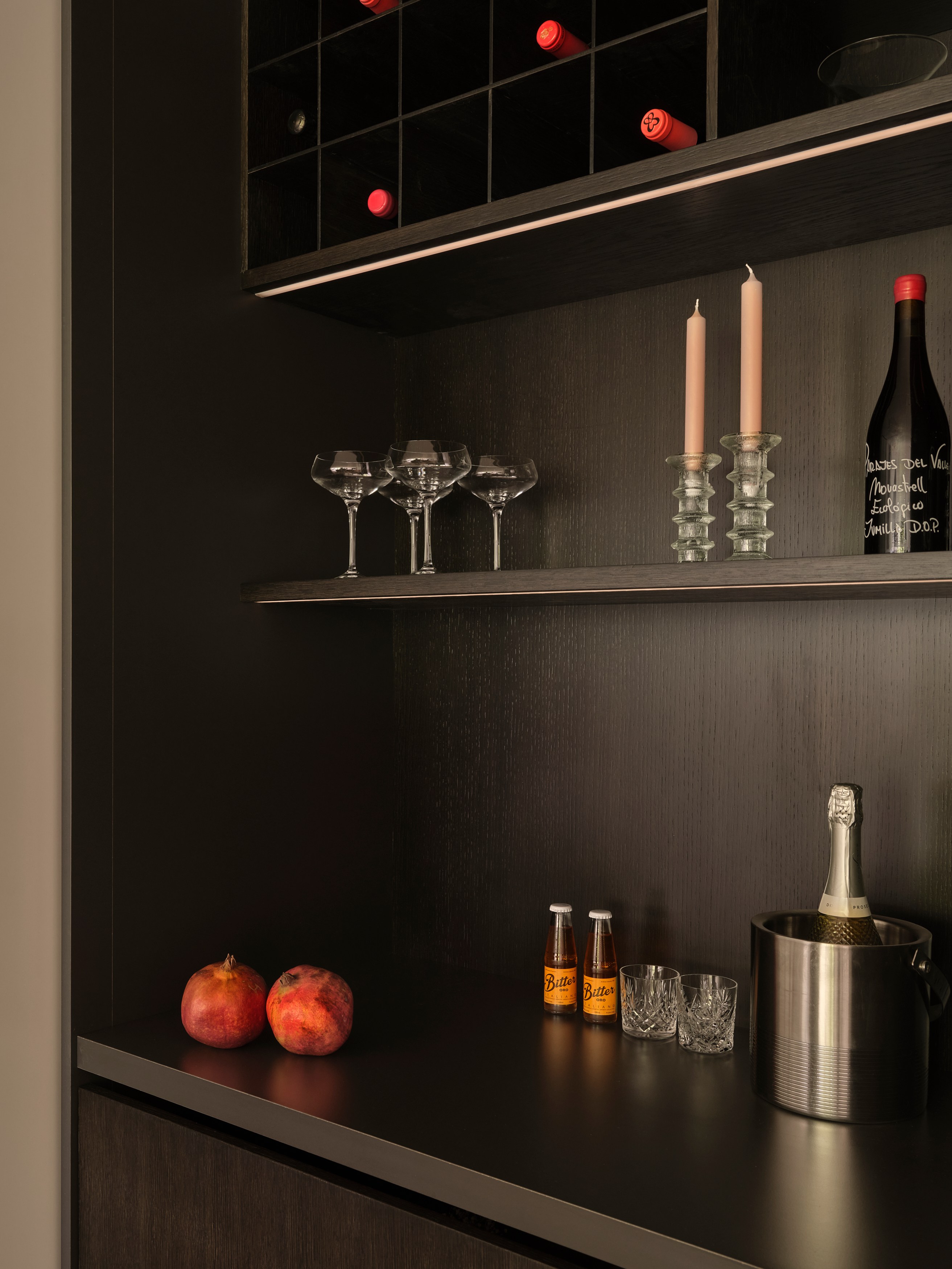 Dark bar cabinet with wine rack, coupe glasses, candlesticks, and prosecco chiller