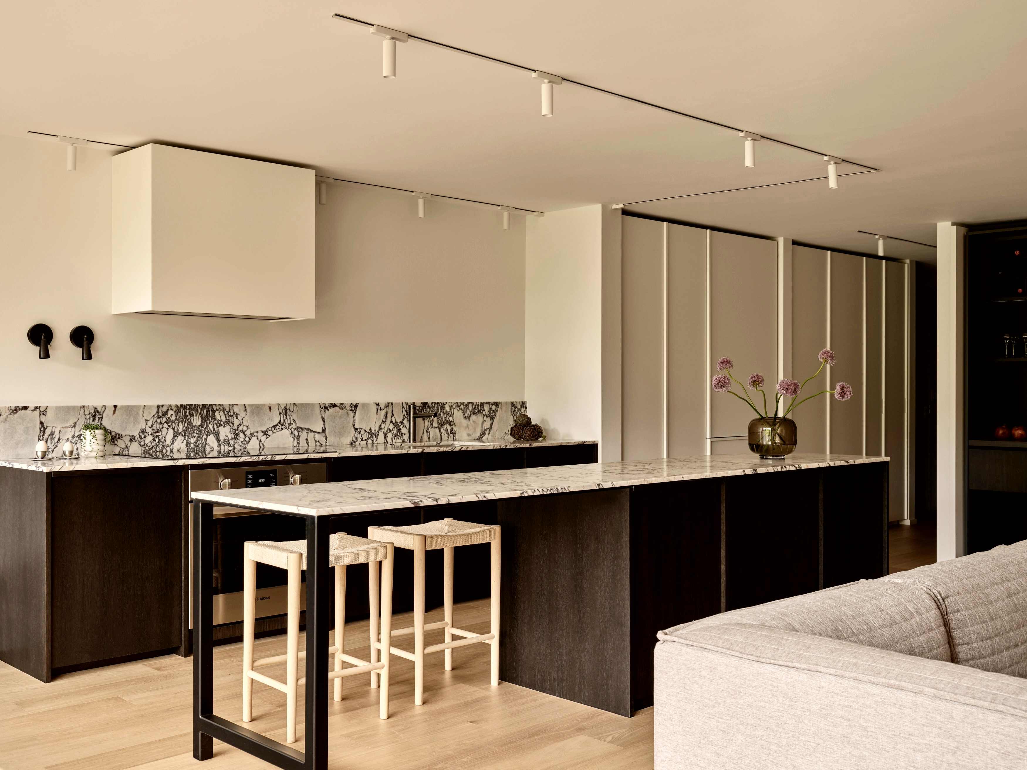 Open kitchen with dark oak cabinetry, Calacatta Viola marble island, and woven counter stools