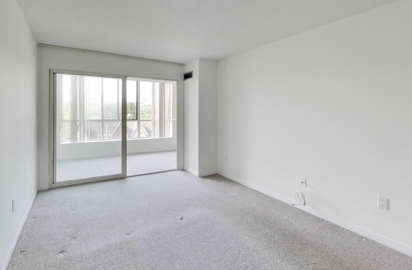 Original carpeted primary bedroom with full-width sliding glass doors before renovation